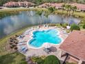 Aerial view of a clover-shaped pool and lounge chairs by a lake in a gated community at 3620 Tresto St, New Smyrna Beach, FL 32168