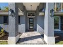 Inviting front entrance with stone pillars, a modern door, stylish lighting, and decorative stone landscaping at 464 Nash Ln, Port Orange, FL 32127