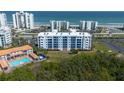 Stunning aerial view of the condo complex, nearby pool, lush greenery, and the beautiful Atlantic Ocean at 5300 S Atlantic Ave # 17-303, New Smyrna Beach, FL 32169