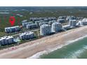 Beautiful beachfront aerial showing condos, sandy beach, and location indicator, near wetlands at 5300 S Atlantic Ave # 17-303, New Smyrna Beach, FL 32169