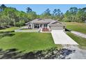 Attractive single-story home with a lush green lawn and a paved driveway leading to the attached two car garage at 53731 Rivertrace Rd, Astor, FL 32102