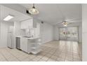 Bright kitchen and living room area features sleek white cabinets and tile flooring at 678 Wellington Station Blvd # 54, Ormond Beach, FL 32174