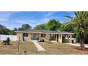 Charming single-story home with a lovely blue front door, a covered carport, and beautifully landscaped yard under a bright blue sky at 10 Lilac Dr, Debary, FL 32713