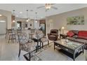 Open-concept living room with neutral tile floors, a ceiling fan, and a clear view of the breakfast bar and kitchen at 1512 Lancashire Way, Deland, FL 32720
