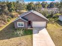 An elevated view of a single-story home featuring neutral stucco siding, a two-car garage and manicured landscaping at 1820 18Th St, Orange City, FL 32763