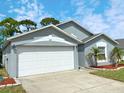This beautiful home features a two car garage, well manicured lawn, and front entrance with vibrant landscaping at 209 Oak Branch Drive, Edgewater, FL 32141