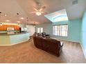 Bright living room boasts a vaulted ceiling, oversized window, and comfortable seating, seamlessly flowing into the kitchen area at 209 Oak Branch Drive, Edgewater, FL 32141
