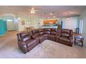 Expansive living room featuring a comfortable wrap around sofa, neutral carpet, and easy access to the kitchen and dining area at 209 Oak Branch Drive, Edgewater, FL 32141