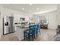 A well-lit kitchen features white cabinets, stainless appliances, a granite island with barstool seating, and tile flooring at 3075 Meleto Blvd, New Smyrna Beach, FL 32168