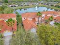 Aerial view of townhomes with red tile roofs overlooking a serene lake with a fountain at 3145 Connemara Dr, Ormond Beach, FL 32174