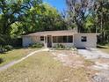 Charming single-story home with a screen door entry and a lush, wooded front yard at 318 S Massachusetts Ave, Deland, FL 32724