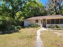 Charming single-story home with a screen door entry and a lush, wooded front yard at 318 S Massachusetts Ave, Deland, FL 32724