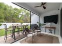 A screened-in outdoor patio featuring a dining table, ceiling fan, TV, and a BBQ grill at 9033 Cape Cod Rd, Deland, FL 32724
