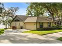 Exterior view of a tan home, showing the driveway, garage, and well-maintained lawn with mature trees at 1227 Baypoint Ct, Longwood, FL 32750