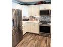 Modern kitchen featuring stainless steel appliances, white cabinets, and stylish backsplash at 1622 Navidad St, The Villages, FL 32162
