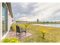 Backyard patio with seating overlooking a tranquil lake, complemented by manicured landscaping and palm trees at 207 Pitching Wedge Dr, Daytona Beach, FL 32124