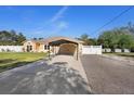 Long driveway leading to a tan home with a matching carport and white fence, under a clear blue sky at 2530 Leonard Dr, Deltona, FL 32725