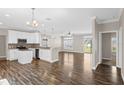 Open-concept living area showcasing hardwood floors, a modern kitchen with white cabinets, and a view to the backyard at 303 Puffer Ct, Kissimmee, FL 34759
