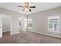 Main bedroom with two windows, neutral walls, carpet flooring, ceiling fan, and a view to the ensuite bathroom at 303 Puffer Ct, Kissimmee, FL 34759