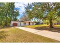 Wide angle shot showing the home and long driveway with ample parking, mature trees, and an attached one-car garage at 816 Overhill Rd, Deland, FL 32720