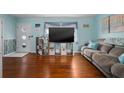 Cozy living room featuring hardwood floors, blue walls, beach decor, and a comfortable sofa at 111 Claire Ter, Daytona Beach, FL 32118
