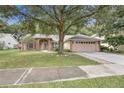 Beautiful one-story residence featuring a lush lawn, a mature shade tree, and a two car garage at 1439 Bent Oaks Blvd, Deland, FL 32724