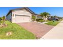 Single-story home featuring a two-car garage, brick driveway and well manicured lawn at 3128 Crab Trap Dr, New Smyrna Beach, FL 32168