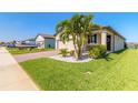 Well-maintained front yard with palm trees, shrubs, and a brick driveway leading to a two-car garage at 3128 Crab Trap Dr, New Smyrna Beach, FL 32168