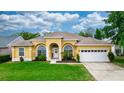 Charming, yellow single-story home featuring arched windows, a well-maintained lawn, and a two-car garage at 316 Oak Springs Dr, Debary, FL 32713