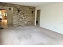 Bright living room featuring a brick wall accent, carpeted floors, and doorways leading to other rooms at 3259 Ellwood Ct, Winter Park, FL 32792