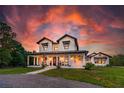 Striking two-story modern farmhouse at sunset, featuring a welcoming front porch and manicured lawn at 1015 Tallacoe Trl, New Smyrna Beach, FL 32168