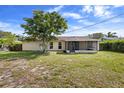 View of the backyard featuring a mature tree, screened in porch, and grassy lawn at 1054 Abeline Dr, Deltona, FL 32725