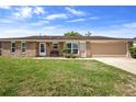 Charming single-story brick home featuring a well-maintained lawn and attached two-car garage at 1054 Abeline Dr, Deltona, FL 32725