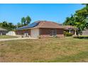 Rear view of brick home with a two car garage and installed solar panels on the roof at 1440 Portola Ave, Deltona, FL 32738