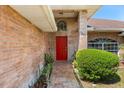 Inviting front entrance with a bright red door, brick facade, and lush green landscaping at 1440 Portola Ave, Deltona, FL 32738