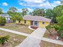 Aerial view of the property showing the yellow house, long driveway, landscaped yard, and surrounding greenery at 1511 Jack St, Tavares, FL 32778