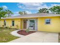Close-up of the front of the yellow house showing brick detail, a bench, and a beautifully landscaped walkway at 1511 Jack St, Tavares, FL 32778