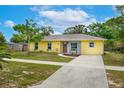 Lovely yellow house with a long driveway and walkway leading to the front door and a beautifully kept lawn at 1511 Jack St, Tavares, FL 32778
