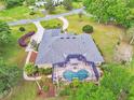Aerial view of a home with screened-in pool, lush landscaping and outdoor patio at 1661 Timber Hills Dr, Deland, FL 32724