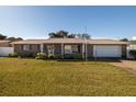 Brick home with a well-maintained lawn, mature landscaping, and a two-car garage at 18 Buckingham Dr, Ormond Beach, FL 32176