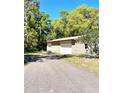 Side view of brick house featuring an asphalt driveway, white garage doors, and lush trees at 2053 Bond Rd, Deland, FL 32720