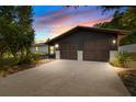 Charming home showcasing a two-car garage, dark exterior paint, and a spacious driveway, enhanced by a colorful sunset backdrop at 265 S Fairbairn Dr, Deltona, FL 32725