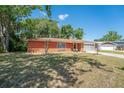 Charming brick home with a manicured lawn and mature trees on a sunny day at 291 Sagewood Dr, Port Orange, FL 32127