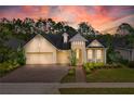 Charming yellow home featuring a three-car garage, landscaped front yard, and inviting entryway at 341 Chelsea Place Ave, Ormond Beach, FL 32174
