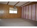 Bright living room with wood paneling, large window, and neutral carpeting, offering a comfortable space at 34416 Oak Ave, Leesburg, FL 34788