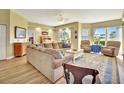 A living room area with a brown sectional sofa and two upholstered chairs on a colorful rug, with light streaming through the windows at 4670 Links Village Dr # B102, Ponce Inlet, FL 32127