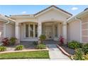 Elegant front entrance with beautiful glass doors, manicured landscaping, and a tiled walkway at 6111 Oxbow Bend Ln, Port Orange, FL 32128