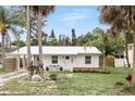 Quaint white home featuring a metal roof, tidy front yard, and mature palm trees at 104 Hester Ave, New Smyrna Beach, FL 32168
