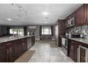 Open kitchen featuring dark wood cabinets, stainless steel appliances, granite countertops, and tiled flooring at 1369 Saxon Blvd, Deltona, FL 32725