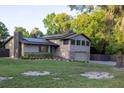 View of a lovely two-story home with green lawn, stone accents, gray siding, and solar panels at 1899 W Beresford Ave, Deland, FL 32720